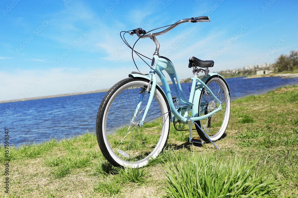 Blue bicycle standing on grass near river