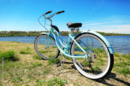 Blue bicycle standing on grass near river