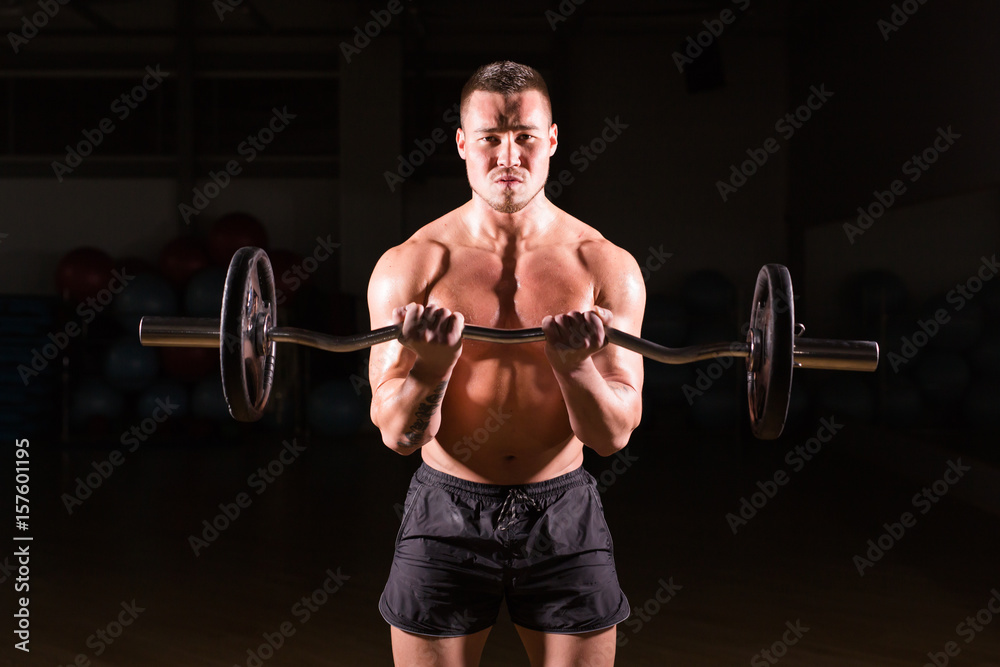 Muscular man working out in gym doing exercises with barbell, strong male naked torso abs. Muscular man working out in gym doing exercises with barbell, strong male naked torso abs.