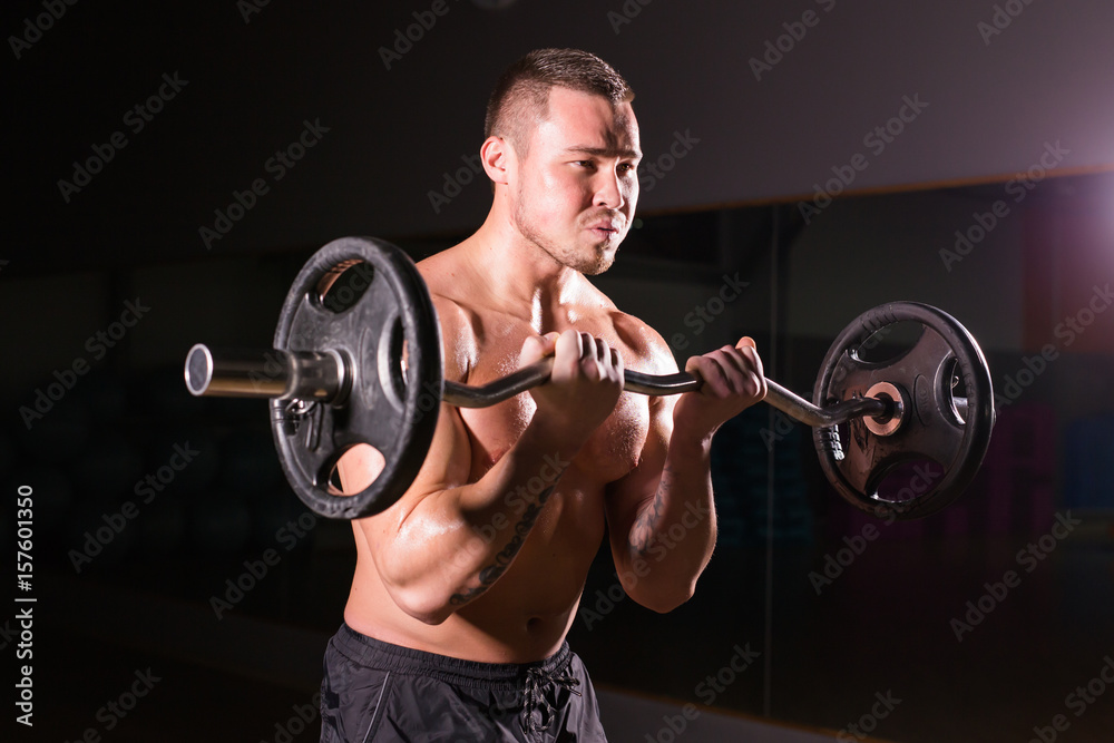 Sporty man doing exercises with barbell on dark background Sporty man doing exercises with barbell on dark background