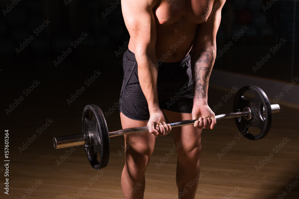 Muscular man working out in gym doing exercises with barbell close-up, strong male naked torso abs. Muscular man working out in gym doing exercises with barbell close-up, strong male naked torso abs.