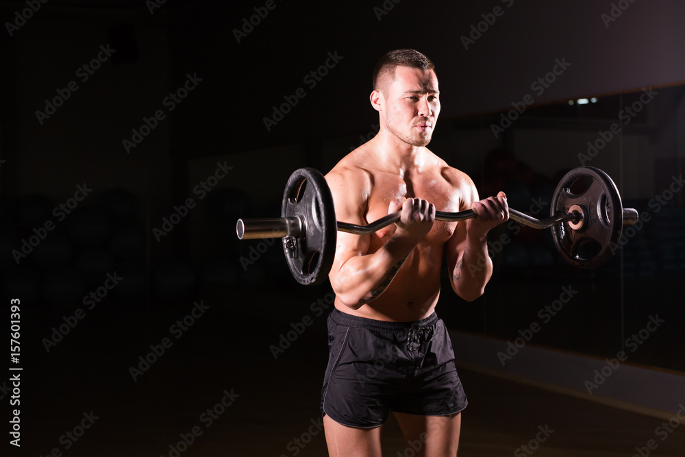 Sporty man doing exercises with barbell on dark background Sporty man doing exercises with barbell on dark background