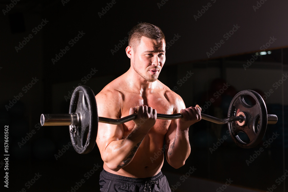 Muscular man working out in gym doing exercises with barbell close-up, strong male naked torso abs. Muscular man working out in gym doing exercises with barbell close-up, strong male naked torso abs.