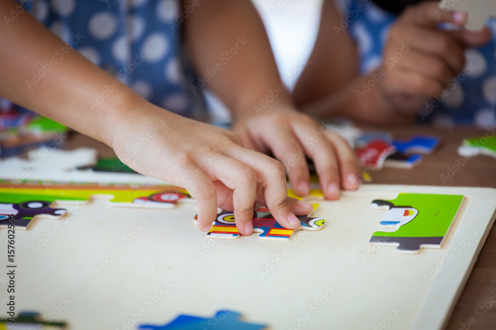 Child little girl hand trying to connect jigsaw puzzle piece to learn to find solution Child little girl hand trying to connect jigsaw puzzle piece to learn to find solution