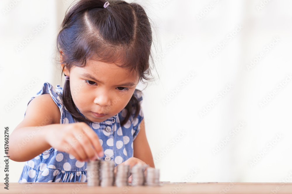 Cute asian little girl playing with coins making stacks of money,kid saving money for the future concept Cute asian little girl playing with coins making stacks of money,kid saving money for the future concept