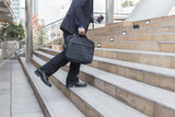 businessman holding bag  while walking upward on the stair outdoor in city.go forward concepts.