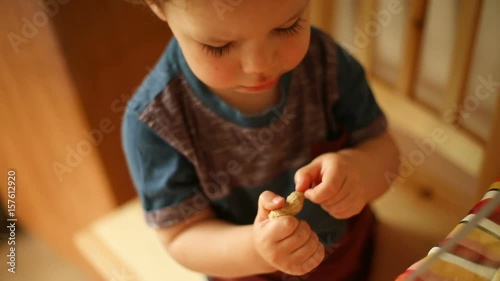 Adorable baby boy tries to open peanut at home and looks very concentrated
