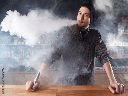Vape. Vaping man in a cloud of vapor. Photo is taken in a vape bar ( shop ).