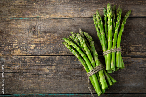 wooden bacckground with bunches of fresh green asparagus photo