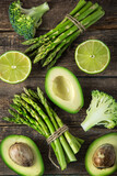 fresh green vegetables (asparagus, avocado, lime, broccoli and green bell  pepper) on wooden background
