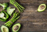 fresh green vegetables (asparagus, avocado, broccoli and green bell  pepper) on wooden background