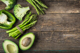fresh green vegetables (asparagus, avocado, broccoli and green bell  pepper) on wooden background