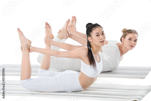 multiethnic girls doing Frog Pose (Bhekasana) isolated on white photo