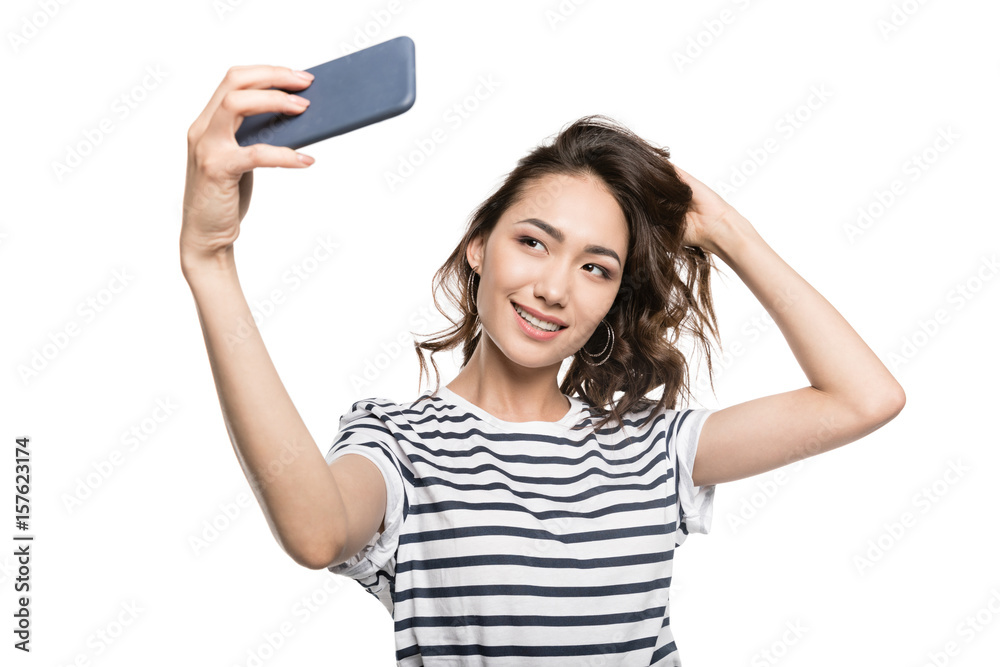 smiling stylish woman taking selfie on smartphone isolated on white