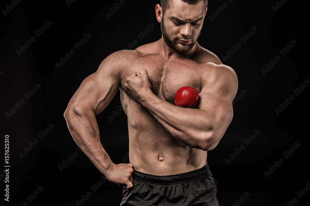 shirtless sportive man holding apple on arm isolated on black