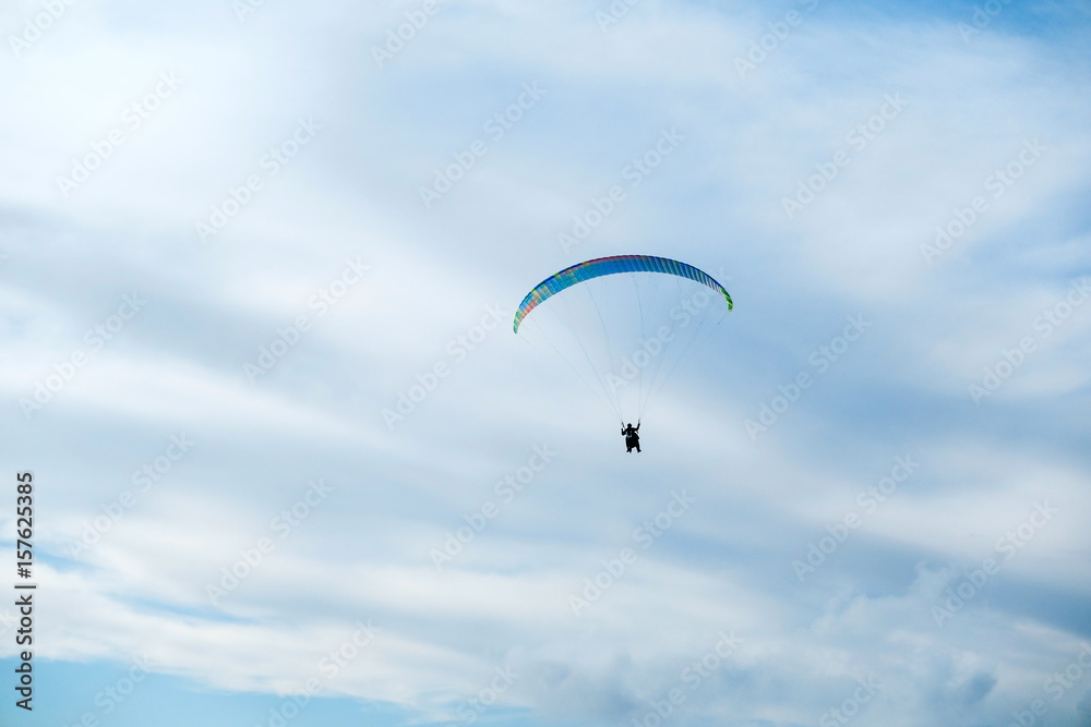 Paragliders in bright blue sky, tandem of instructor and beginner Paragliders in bright blue sky, tandem of instructor and beginner