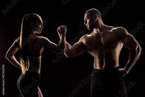 young sporty couple holding hands isolated on black
