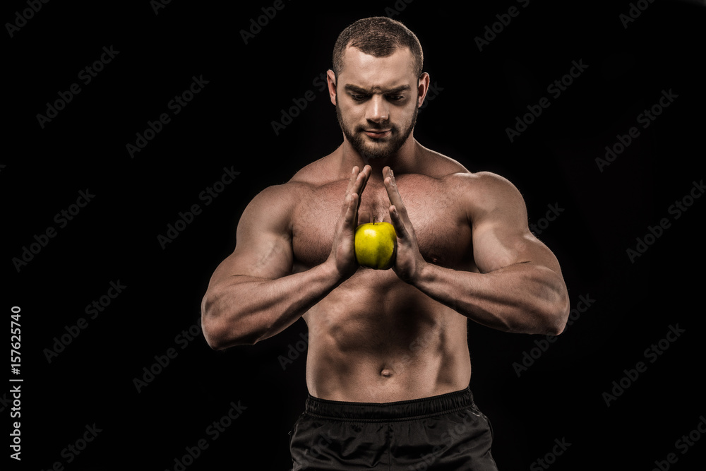 shirtless sportive man holding fresh apple isolated on black