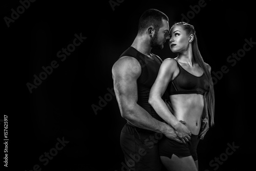 sensual sportive couple wearing sportswear, hugging and looking at each other isolated on black, black and white © LIGHTFIELD STUDIOS