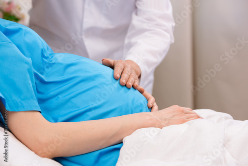 cropped view of doctor touching belly of pregnant woman lying in clinic