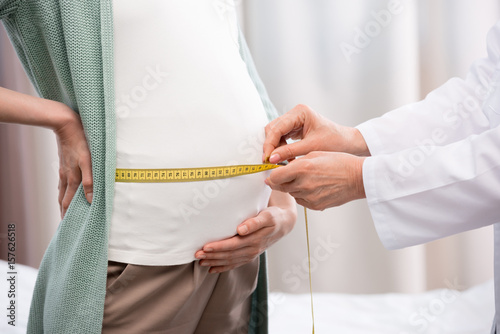 partial view of doctor measuring belly of pregnant woman in hospital