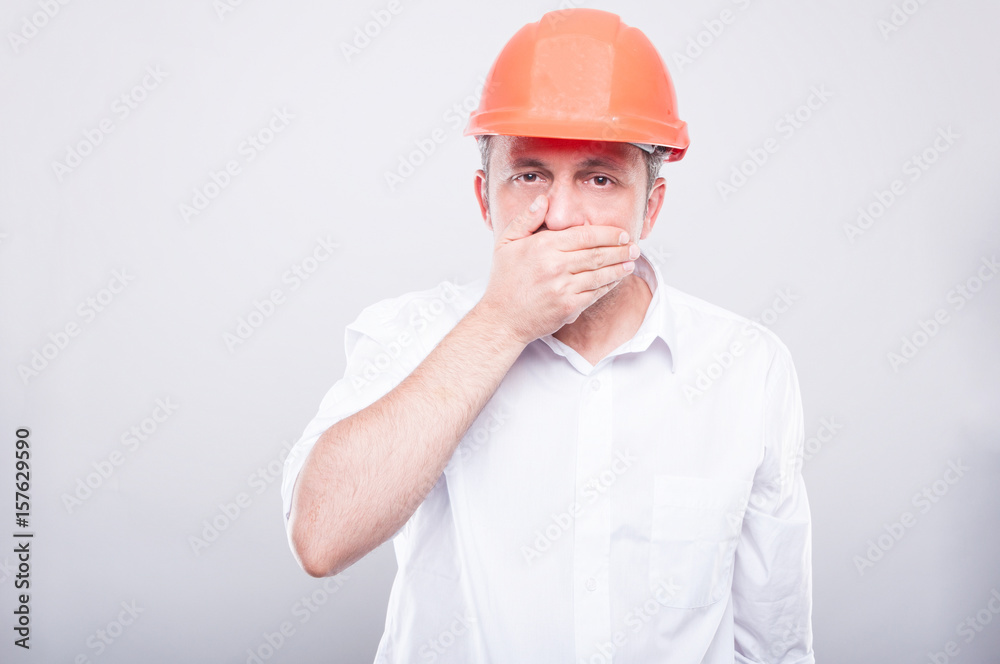 Portrait of contractor wearing hardhat covering his mouth Portrait of contractor wearing hardhat covering his mouth