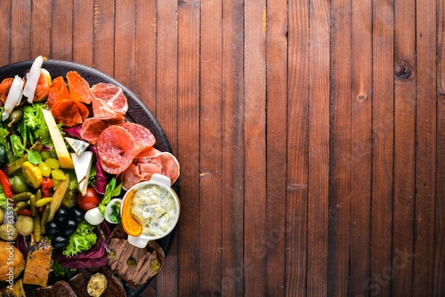 Cold appetizers, meat and pickled vegetables. Italian cuisine. Top view. On Wooden background.