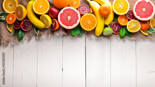 Fresh citrus fruits. Lemon orange, tangerine, lime, banana. On a white background Wooden. Top view.