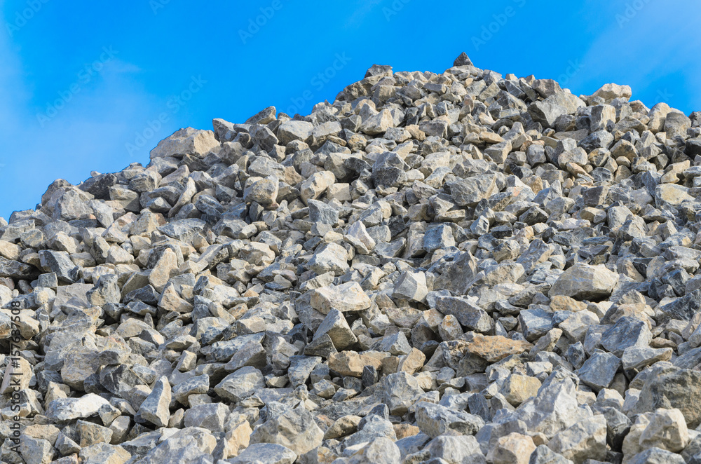 Pile of gray gravel stones with blue sky and clouds background Pile of gray gravel stones with blue sky and clouds background