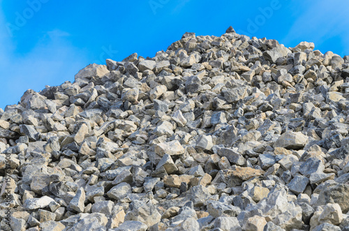 Pile of gray gravel stones  with blue sky and clouds background © ognjeno