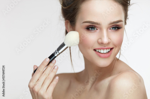 Beauty Face Makeup. Beautiful Smiling Girl Applying Loose Blush