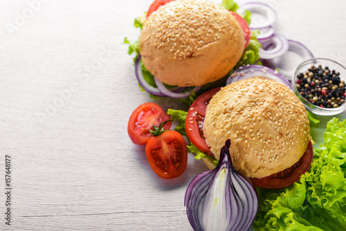 Hamburger with cheese, meat, tomatoes and onions and herbs. On Wooden background. Top view. Free space.