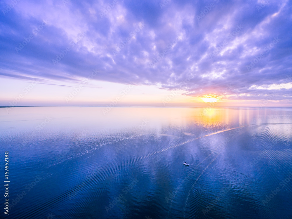 Aerial view of beautiful sunrise - lonely boat in the vast ocean. Nothing but sky, boat and water Aerial view of beautiful sunrise - lonely boat in the vast ocean. Nothing but sky, boat and water