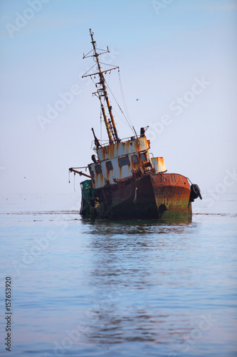 Rusty ship near the river Burka flowing into the Pacific Ocean in Severo-Kurilsk town on Paramushir Island on sunny weather.