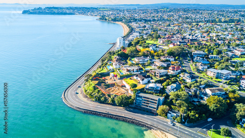 Aerial view on a road running along sea shore with residential suburbs on the background. Auckland, New Zealand.