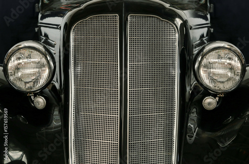 Front headlights and grille of a restored vintage car and hood ornament, close up frontal. Vintage