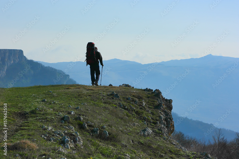 A tourist on a mountain plateau. The contour of a person walking with a backpack on the edge of the mountain.