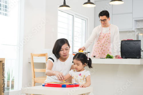 asian family studying while father is cooking photo