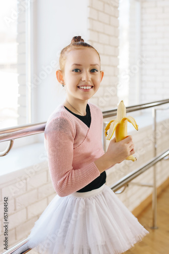 Foto Girl ballerina eating a banana in ballet class