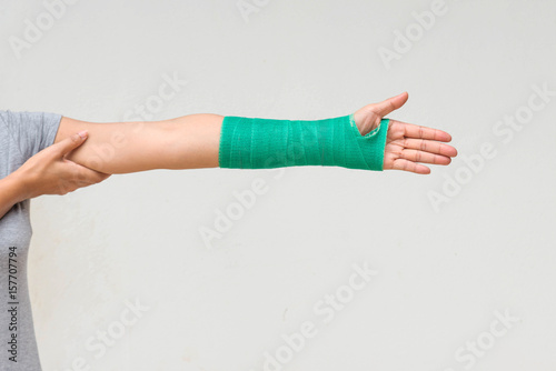 Injury woman wearing sports ware with green cast on hand and arm, body injury concept