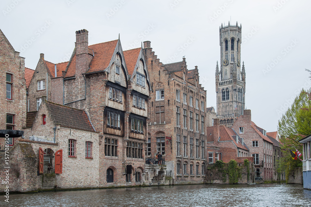 Old town of Bruges (Brugge) with brick houses above canal and famous Belfry on the background, Belgium