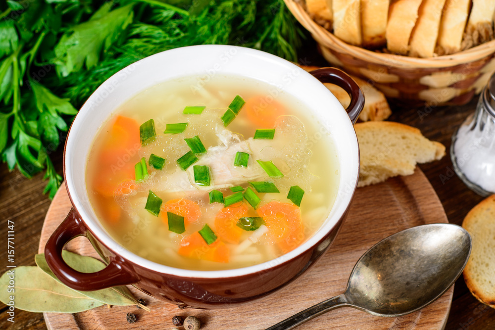 Homemade chicken soup with noodles and vegetables in ceramic bowl on wooden table. Homemade chicken soup with noodles and vegetables in ceramic bowl on wooden table.
