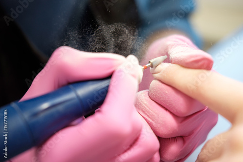 Manicurist polishing nails using polish machine