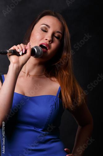 Beautiful young singer holding microphone