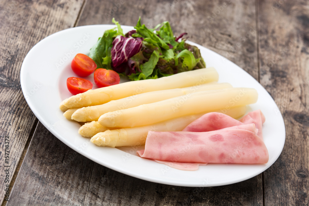 White asparagus with salad and ham on wooden background
White asparagus with salad and ham on wooden background
