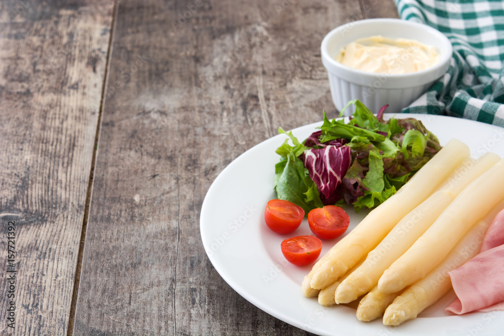 White asparagus with salad and ham on wooden background
White asparagus with salad and ham on wooden background