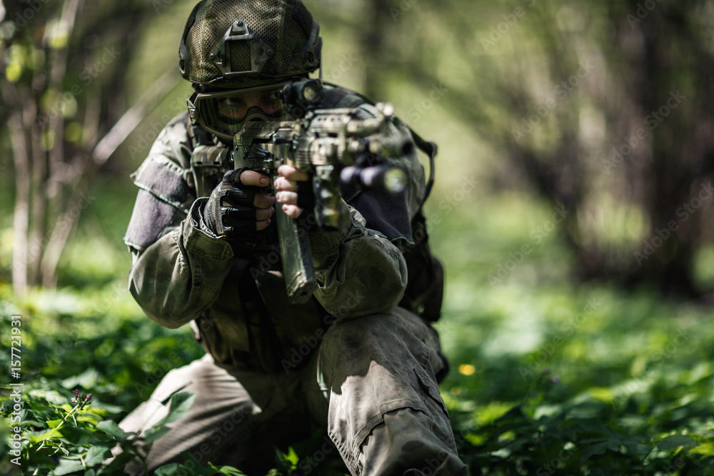 Soldier aiming in woods during day