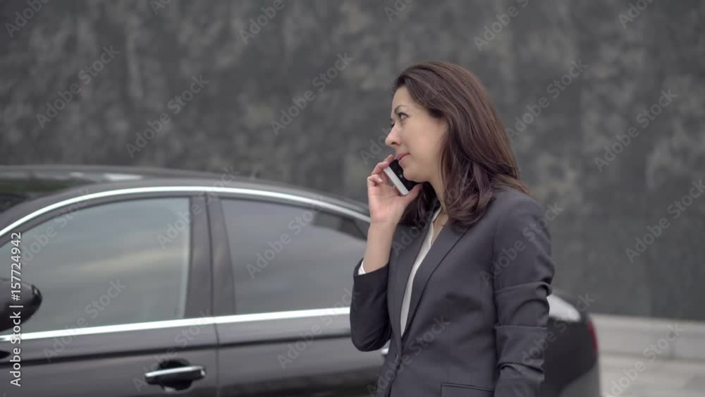 Successful business woman leadership position standing near the business class car and talking on the cell phone, UHD 4K Successful business woman leadership position standing near the business class car and talking on the cell phone, UHD 4K