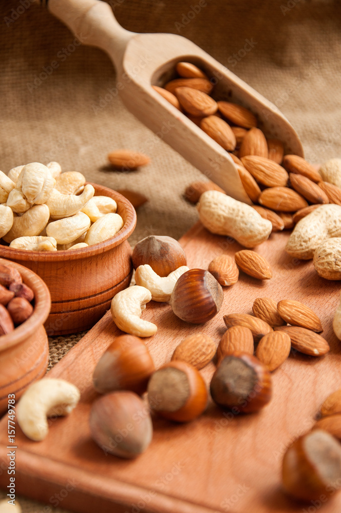Almonds, cashew and hazelnuts in wooden bowls on wooden and burlap, sack background