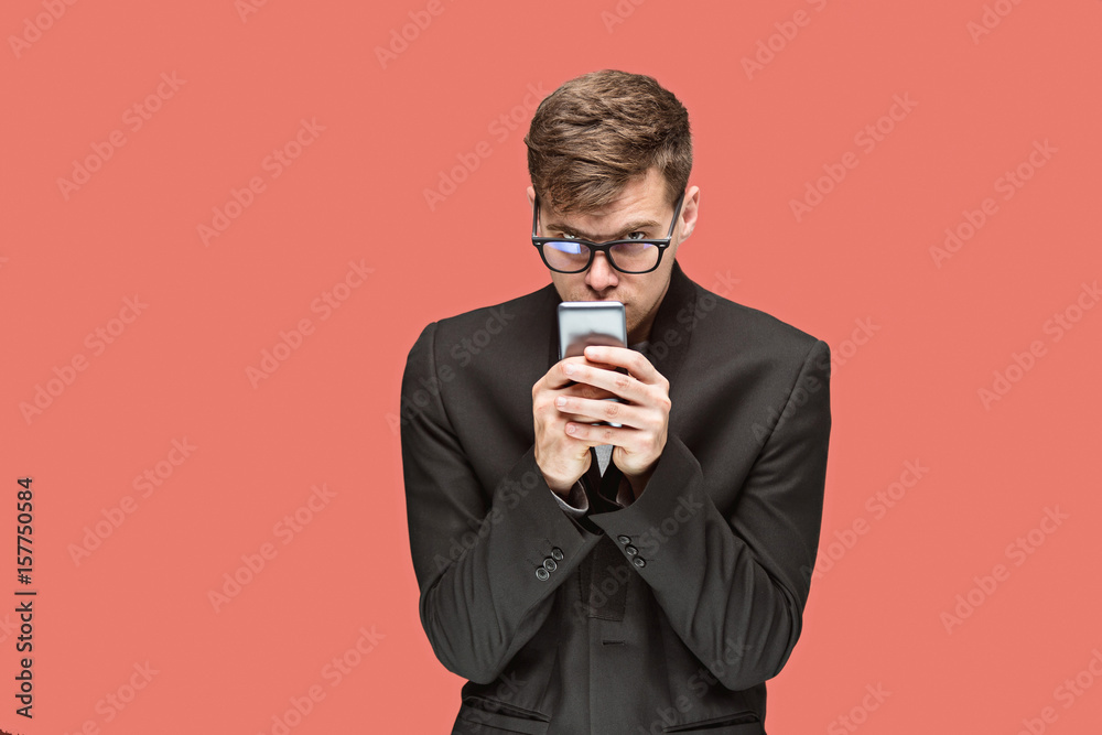 The young caucasian businessman on red background talking on cell phone The young caucasian businessman on red background talking on cell phone